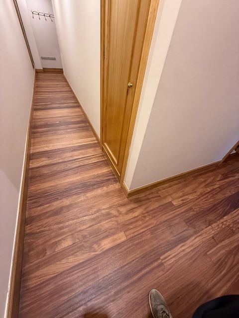 Pasillo con suelo de madera barnizado hasta la puerta