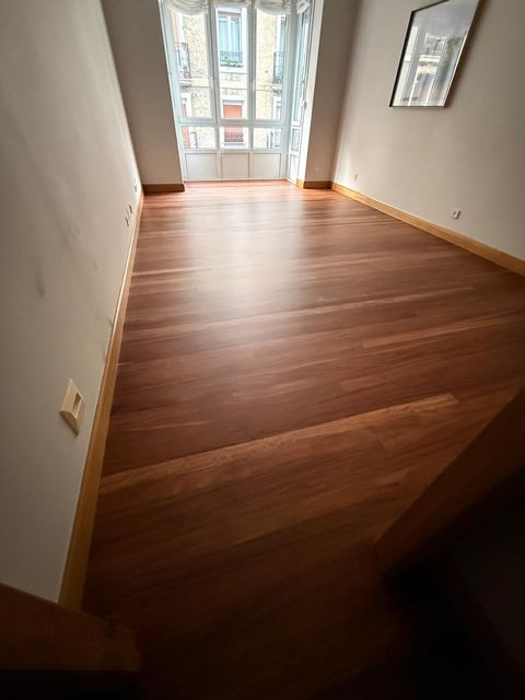 Salón con suelo de madera barnizado y ventanal