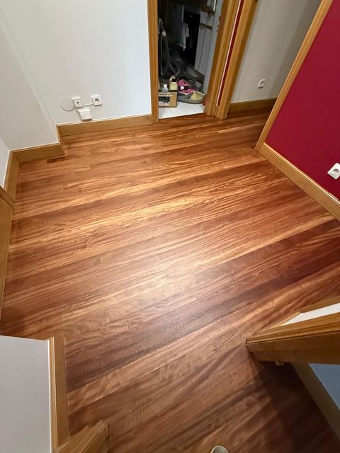 Habitación con tarima de madera barnizada y pared roja