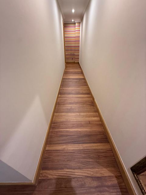 Pasillo largo y estrecho con tarima de madera barnizada