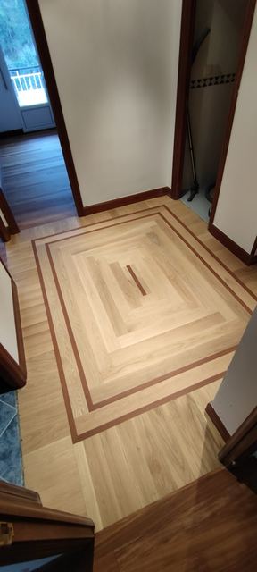 Parquet claro con cenefa en forma de marco en la entrada de una casa