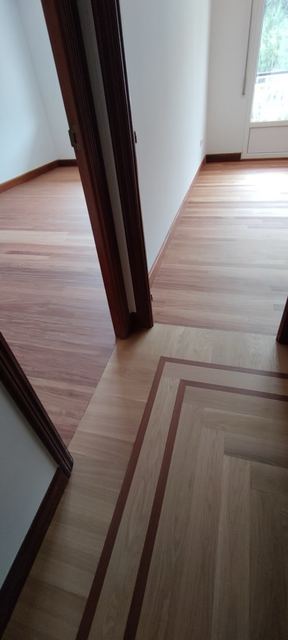 Suelo de madera clara con cenefa junto a una puerta